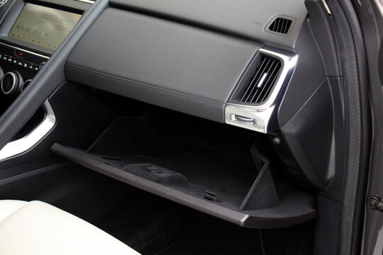 Open glove box in new car. Modern car passenger airbag. Glove compartment in white car interior. Detail of new electric car interior. White leather interior.