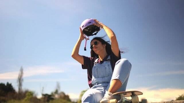 Young woman wearing sunglasses and overalls putting on her helmet