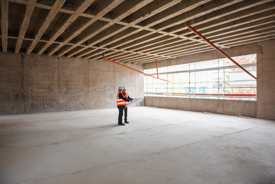 Engineers inspecting a shell construction site indoors with blueprints