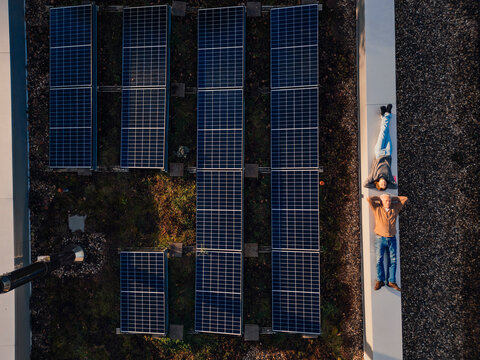 Grandfather and granddaughter relaxing on a rooftop with solar panels