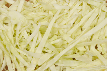 A close-up, top-down view of freshly shredded white cabbage, showcasing its light color and delicate texture