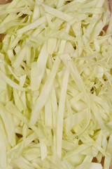 A close-up, top-down view of freshly shredded white cabbage, showcasing its light color and delicate texture
