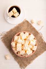 Fototapeta premium Orange and pink marshmallow in ceramic bowl on white wooden background, top view, copy space