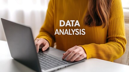 Fototapeta premium A person in a yellow sweater is typing on a laptop, focusing on data analysis in a bright, cozy workspace.