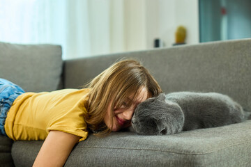 Teen girl and Scottish Fold cat rest together in cozy home setting, showcasing a moment of friendship and relaxation