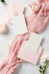 Romantic flat lay of pink envelopes, blank cards, roses, and soft fabric. Ideal for wedding...
