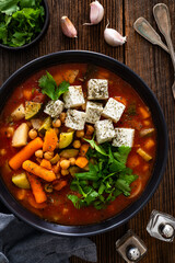 Fresh vegetable soup with chickpeas, feta cheese and cilantro on wooden table