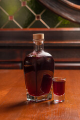 Alcoholic berry tincture glass bottle on wooden table
