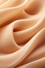 Fototapeta premium A soft, peach-colored fabric drapes gracefully, revealing delicate folds and a smooth texture. The warm tones create a serene and inviting atmosphere