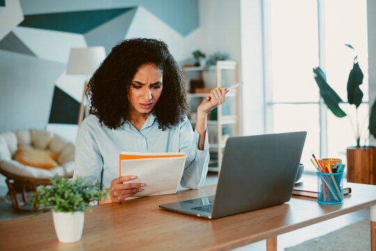 Young female student focused on work in a cozy home office setting during daylight