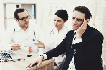 Businessman with headache in neurologist at reception. Treatment of migraine. Cluster headache.