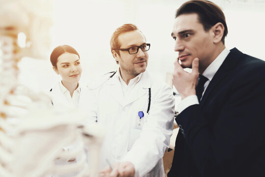 Anxious businessman at reception with physiotherapist in medical office. - Powered by Adobe