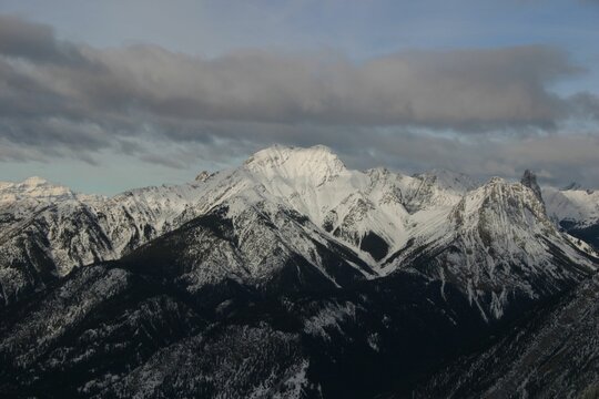 Snow-capped mountains under cloudy sky.