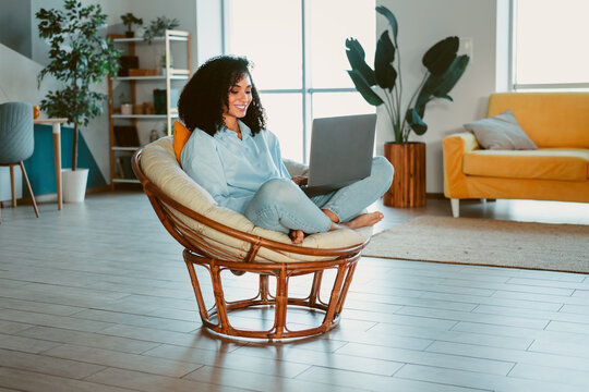 Young woman working on a laptop from the comfort of her elegant living room, enjoying a peaceful and creative remote working