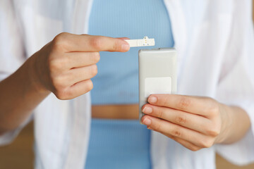 Girl sitting with sensor glucose patch on her arm looking at the monitor results