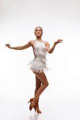 Elegant female dancer in a dynamic Latin pose, wearing a white fringe dress and high heels, exuding...