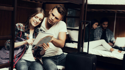 Girl and Man sit on bed and look at Map Together