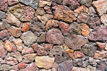 colored unprocessed rocky stones of natural origin, a wall of stones in concrete, background for walls and wallpapers