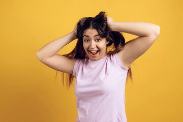 Young joyous girl ruffles long hair on head.