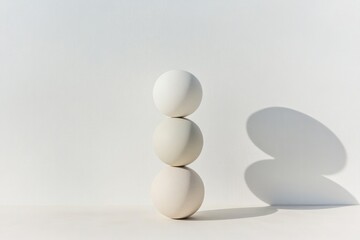 Three white spheres delicately balanced, casting soft shadows on