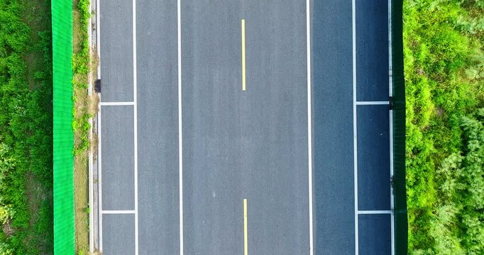 Aerial view of empty asphalt road with white lines marking lanes. Transportation background.