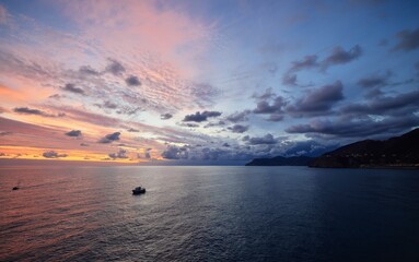 Serene seascape at sunset with vibrant skies and boats.