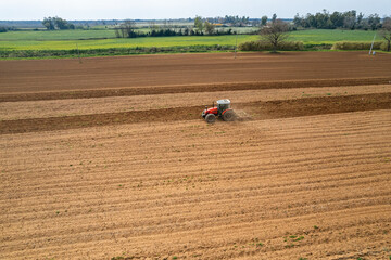 Fototapeta premium An aerial view of a Tractor tilling a field in the spring. Spring field work on a tractor