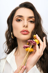 Fototapeta premium Beautiful young woman with brown hair holding flowers in a spring ambiance
