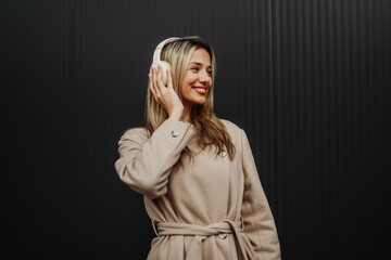 Portrait of a teenage girl smile and listen to music on wireless headphones
