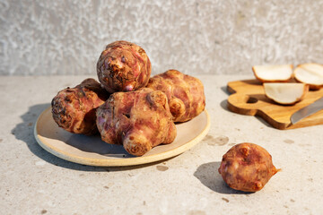Organic Jerusalem artichoke tubers displayed on a plate over a marble countertop.
