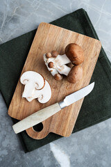 Close-up of fresh brown champignon mushrooms, whole and sliced, arranged on a wooden cutting board.