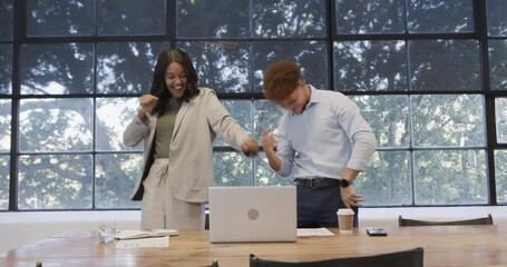 Celebrating success, business diverse colleagues feeling excited with laptop in modern office