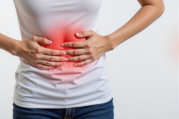 A Young Asian Woman Experiencing Abdominal Pain While Standing Against a White Background – Symptoms of Discomfort and Health Issues