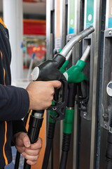 Man holding fuel pump nozzle at gas station
