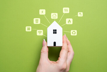 Hand holding a house with holograms of housing service utilities. Digital infrastructure, smart...