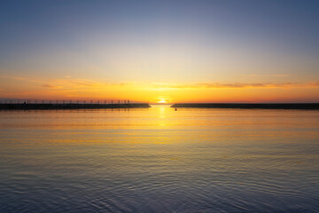 The sun setting over the sea in the middle of the breakwater entrance. Rosignano Solvay, Tuscany, Italy
