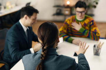 Businesswoman sitting at table with her colleagues and discussing plans during meeting in office