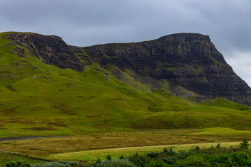 Naklejka premium Neist Point at sunset is a breathtaking sight—its lighthouse stands against dramatic cliffs, with waves crashing below. A rainbow arches over the ocean, painting the rugged Isle of Skye magical light