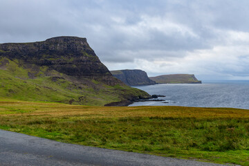 Neist Point at sunset is a breathtaking sight&mdash;its lighthouse stands against dramatic cliffs, with waves crashing below. A rainbow arches over the ocean, painting the rugged Isle of Skye magical light