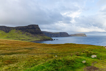 Neist Point at sunset is a breathtaking sight&mdash;its lighthouse stands against dramatic cliffs, with waves crashing below. A rainbow arches over the ocean, painting the rugged Isle of Skye magical light