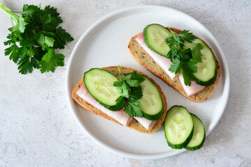Sandwich with Ham, Cucumber and Parsley on plate top view