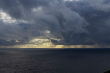 Neist Point at sunset is a breathtaking sight—its lighthouse stands against dramatic cliffs, with waves crashing below. A rainbow arches over the ocean, painting the rugged Isle of Skye magical light