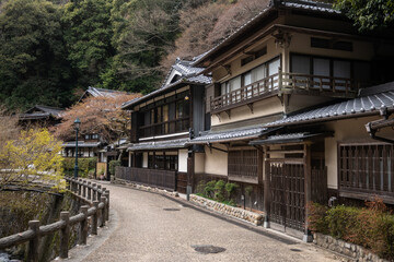 Preserved Edoera architecture lines a narrow street nestled in the mountains in Minoh National Park, Osaka, Japan. Traditional wooden houses with dark roofs.