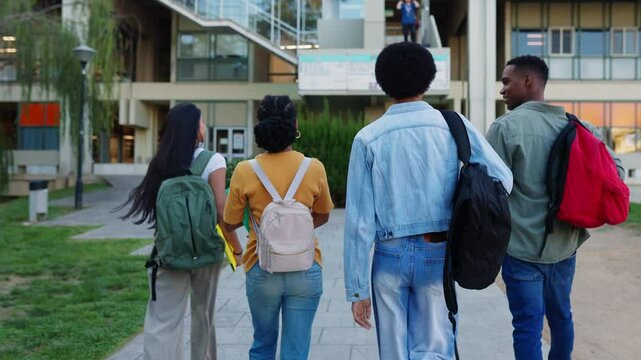 Rear view of young group of American student friends walking around university campus going to college classes. Education and back to school concept.