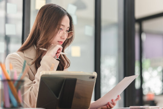 Young professional analyzes documents while working in modern office environment for improved productivity
