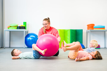 Kids group physical therapy. Children and female physical therapist exercising during session. Bilateral coordination or integration.