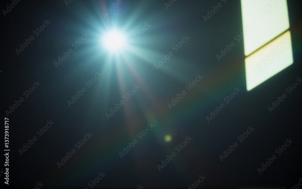 Poster Bright light source with lens flare illuminates a dark space.  A bright glow with rays and rainbow effect shines, possibly from a window, casting light in the darkness.