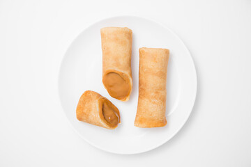 pancakes with condensed milk on a white plate on a white background top view