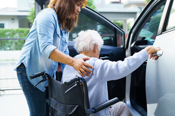 Caregiver help Asian elderly woman disability patient use wheelchair to get in car.