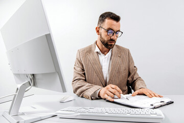 Tired, focused business man working at a computer in a bright office. The man looks frustrated while working. The concept of stress, frustration and burnout in the workplace.